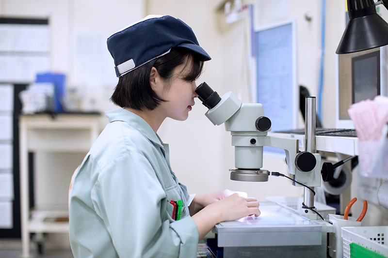 顕微鏡を使って作業する東新工業の社員